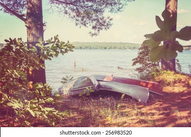 Canoes pulled up on the shore, with kids playing in the lake. Vintage Instagram effect. - Powered by Shutterstock