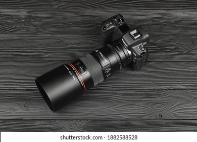 Canon EOS R Photocamera And Mount Adapter EF - EOS R With Canon 105mm F2.8 Lens On Black Wooden Table. Photography Equipment By Canon Inc.