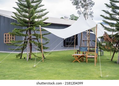 Canopies anchored to steel structures provide shade. White tarpaulin taut, shading from the sun and rain. wooden table and chair