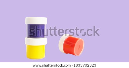  Cans of colored gouache paint isolated on colored lilac background                              