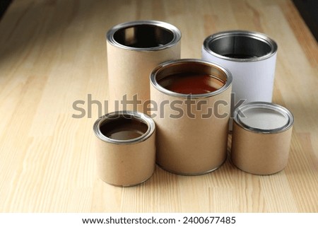 Cans with different wood stains and varnish on wooden surface