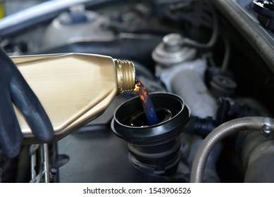 From cans of oil pouring oil in car engine