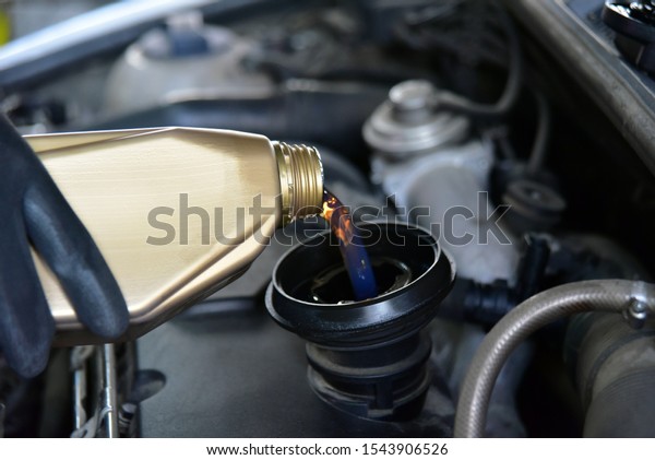 From cans of oil\
pouring oil in car engine