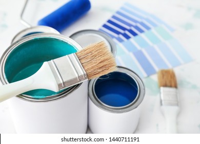 Cans of paint with brush on table, closeup