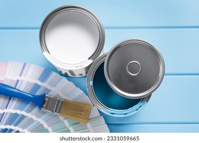 Cans of paints, brush and palette on light blue wooden table - Powered by Shutterstock