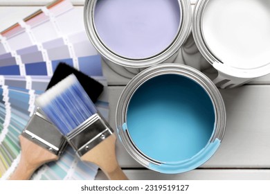 Cans of paints, brushes and palette on white wooden table, flat lay - Powered by Shutterstock