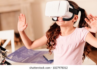 It Cant Be Real. Amazed Preteen Child Gesturing And Smiling Cheerfully While Wearing A VR Headset Indoors.