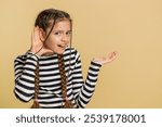 I cant hear you. What. Child girl kid trying hear you, looking confused and frowning, keeping arm near ear for louder voice asking to repeat to hear information deafness. Children on beige background