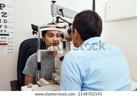 Can't see Come to me. Shot of a young woman getting her eyes examined with a slit lamp by an optometrist.