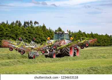 Canterbury, New Zealand - November 17 2018: A Green Fendt Tractor And Tedder Working In A Farm Field Raking Cut Grass Into Rows For The Hay Baler