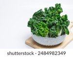 Cantonese Bok Choy, white stalks of crinkled green leafy vegetables Eat healthy, fibrous foods in a bowl on a wooden cutting board.