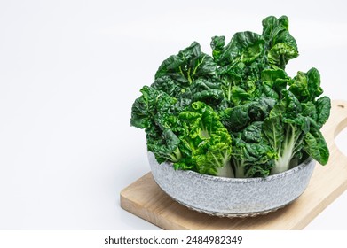 Cantonese Bok Choy, white stalks of crinkled green leafy vegetables Eat healthy, fibrous foods in a bowl on a wooden cutting board. - Powered by Shutterstock