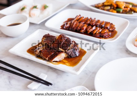 Cantonese roasted duck meat with duck roasted sauce with BBQ Pork in background.