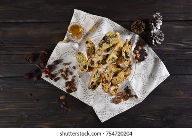 Cantucci assorted with pistachio nuts, almonds, cranberries, chocolate, hazelnuts, and vinsanto on a wooden table