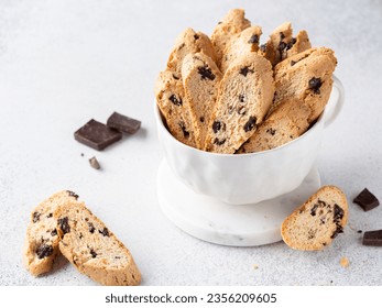 Cantucci with chocolate pieces in white cup. Italian classic biscotti with dark chocolate chips and orange zest. Close up view. Homemade crunchy biscuits. Copy space. White background. - Powered by Shutterstock