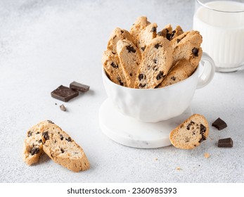 Cantucci with chocolate pieces in white cup served witha glass of milk. Italian classic biscotti with dark chocolate chips and orange zest. Close up view. Homemade crunchy biscuits, tasty snack. - Powered by Shutterstock