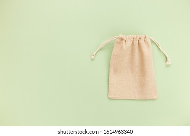 Canvas Bag With Drawstring, Mockup Of Small Eco Sack Made From Natural Cotton Fabric Cloth Flat Lay On Green Pastel Background From Top View