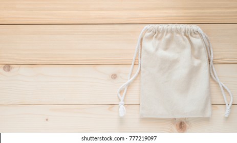 Canvas Bag With Drawstring, Mockup Of Small Eco Sack Made From Natural Cotton Fabric Cloth Flat Lay On White Wood Background From Top View 