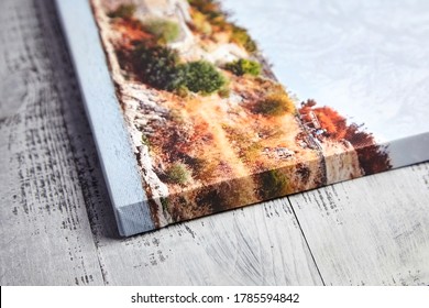 Canvas print on wooden background. Wrapped canvas, edge, corner, closeup. Detail of stretched landscape photography with gallery wrapping. Photo printed on canvas