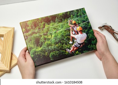 Canvas print. Photo with gallery wrap method of canvas stretching on wooden stretcher bar. Female hands hold a color travel photography (with people on zip line) 