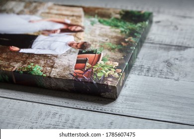 Canvas print. Photo printed on canvas. Sample of stretched wedding photography with gallery wrap, side view, closeup. Portrait on grey wooden surface