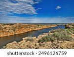 The canyon of the Yardie Creek in Cape Range National Park, Western Australia, with red and yellow limestone rocks and stunted outback vegetation
