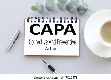 CAPA Corrective and Preventive action plans. text on white notepad paper. near cups with coffee and plants on a gray background.