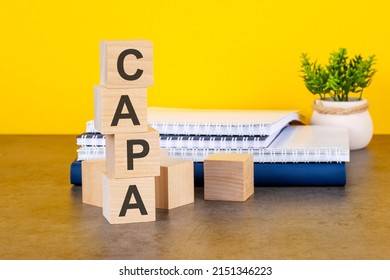 capa word written on wooden cubes with copy space, yellow background. capa - short for corrective and preventive action plans