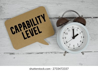 Capability Level text with alarm clock on wooden background