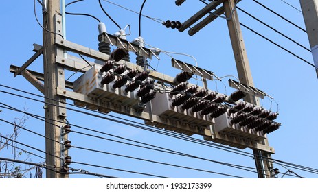 Capacitor banks on electric poles. Rows of voltage stabilizing devices (AC or DC) on power transmission lines for maximum efficiency and reduced voltage loss on a blue sky background. Selective focus
