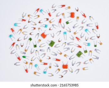 Capacitors. Different type in different colors. Colorful small ceramic, metal, film capacitors. Green, blue, orange, red capacitors. On white background. Top view.