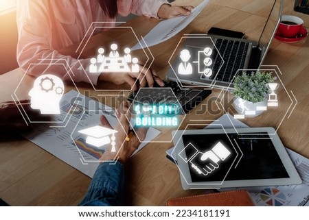 Capacity building concept, Mature businessman discuss information with a younger colleague with virtual graphic capacity building icon diagram.	

