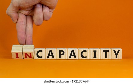 Capacity or incapacity symbol. Businessman turns wooden cubes and changes the word 'incapacity' to 'capacity'. Beautiful orange background. Business and capacity or incapacity concept. Copy space.