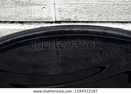 Capacity with rainwater on the background of the wooden wall of the house. Texture of water with reflection. Clean water. Selective focus.