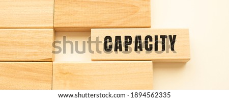 CAPACITY text on a strip of wood lying on a white table. Concept.