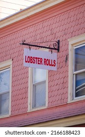 Cape May, New Jersey - September, 2021: A white sign that says Lobster Rolls in red letters seen hanging from a house with pink wooden shingles on this small New Jersey town