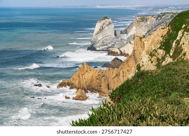 Cape Roca (Cabo da Roca) cliffs overlooking the Atlantic Ocean in Sintra, Portugal. Rocky coastline with crashing waves. The sun shines brightly over the blue ocean water.