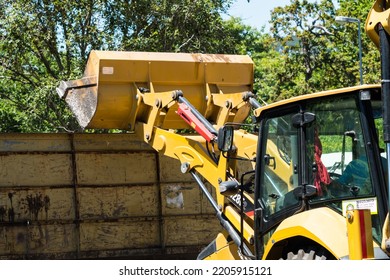 Cape Town - November 29, 2019:  Yellow CAT Front End Loader Or Heavy Machinery Tipping A Load Into A Metal Container With Selective Focus On The Bucket Concept Construction Industry