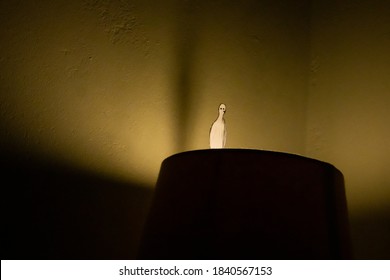 Cape Town, South Africa - 05/20/20

Paper Doll Man, Standing On Top Of A Lamp Shade, Staring Into The Bright Yellow Light. Appearing Lonely And Melancholic, But Focusing On The Light.