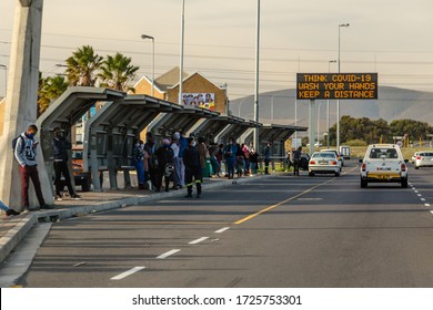 Cape Town, South Africa - 06 May 2020: South African Bus Stop During Corona Virus Pandemic Lock Down. Struggle To Survive Poverty, Face Masks, Social Distancing. Road Sign With Covid 19 Warning.