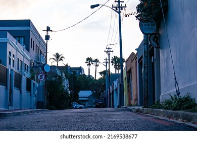 Cape Town, South Africa 18-06-2022

Quiet Street Near Bayview Terrace During Sunset. Colorful Buildings And Road In Foreground.