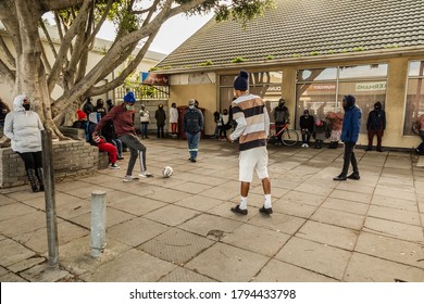 Cape Town, South Africa - August 2020: Young African Men Play Football While Waiting In Line For Covid Relief Fund In South Africa