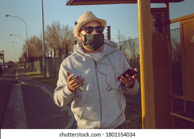 Cape Town, South Africa - August 2020: African Mixed Race Man Gets Left Behind Waiting At Bus Stop Using Smart Phone, Wearing Face Mask For Protection