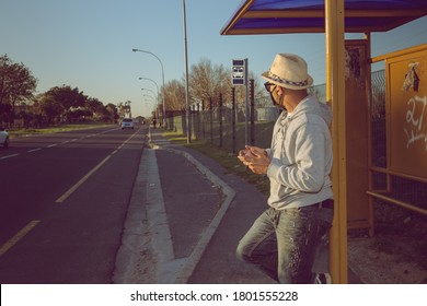 Cape Town, South Africa - August 2020: African Mixed Race Man Waiting At Bus Stop With Face Mask For Corona Virus Pandemic In Africa
