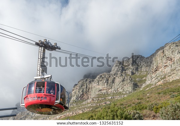 CAPE TOWN, SOUTH AFRICA, AUGUST 17, 2018: Viiew of\
the Table Mountain Cableway as seen from the lower cable station at\
Table mountain. A cable car is visible. The cables disappear into\
the clouds