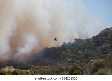 CAPE TOWN, SOUTH AFRICA - JAN 11 2017. Helicopter Being Used To Collect Water From A Local Lake To Fight Wild Fire In The Mountains Behind The Glencairn Suburb Of Cape Town.