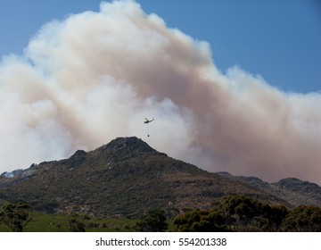 CAPE TOWN, SOUTH AFRICA - JAN 11 2017. Helicopter Being Used To Collect Water From A Local Lake To Fight Wild Fire In The Mountains Behind The Glencairn Suburb Of Cape Town.