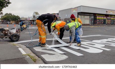 Cape Town, South Africa - May 2020: Road Workers Spraying Fresh Traffic Lines On Stop Sign, Maintenance And City Upgrade. Economic Development In Africa. Protective Masks Corona Virus Pandemic