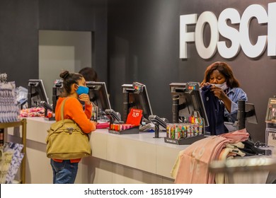 Cape Town, South Africa - November 2020: Mixed Race Woman Shopping During Corona Virus Pandemic In Africa. Retail Shop Assistant Wearing Face Mask For Covid 19 Protection.