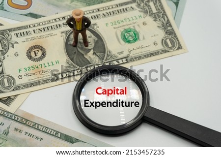 Capital Expenditure.Magnifying glass showing the words.Background of banknotes and coins.basic concepts of finance.Business theme.Financial terms.